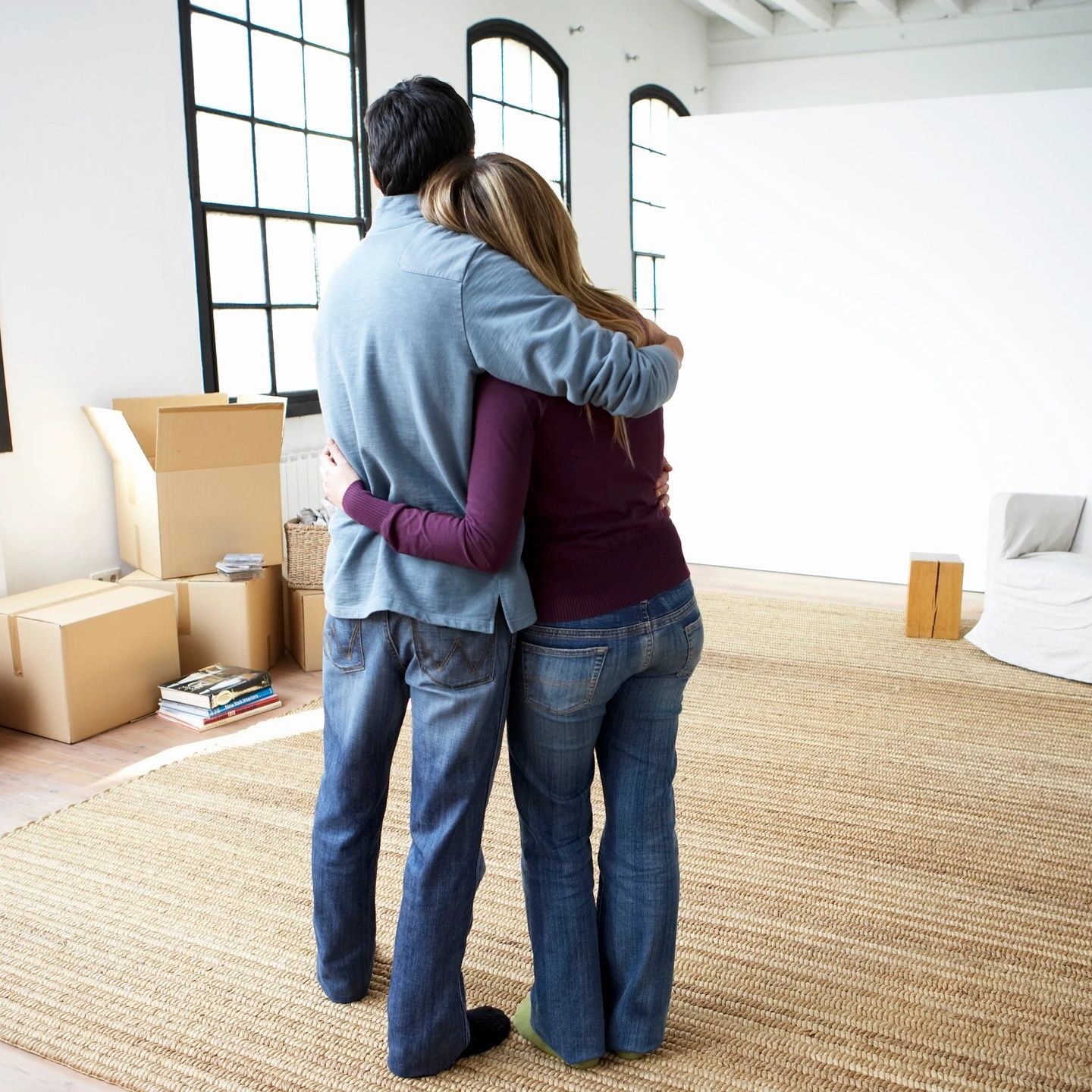 Couple hugging in new apartment surrounded by boxes